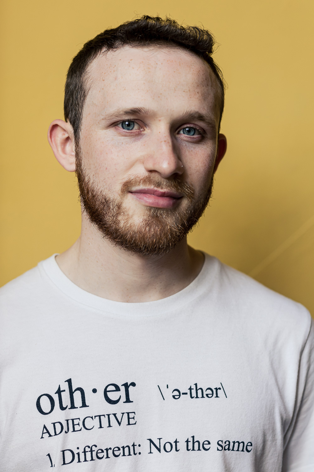 Headshot of Jack Guy. Jack is against a yellow backdrop wearing a tshirt with the defintion of 'other'.