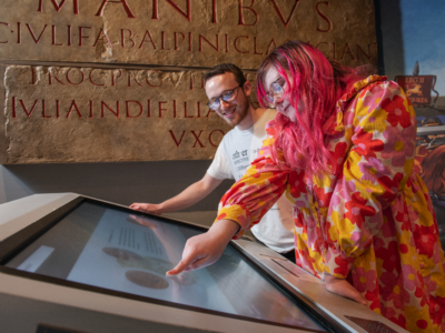 Two Curating for Change Fellows look at a screen in the Museum of London